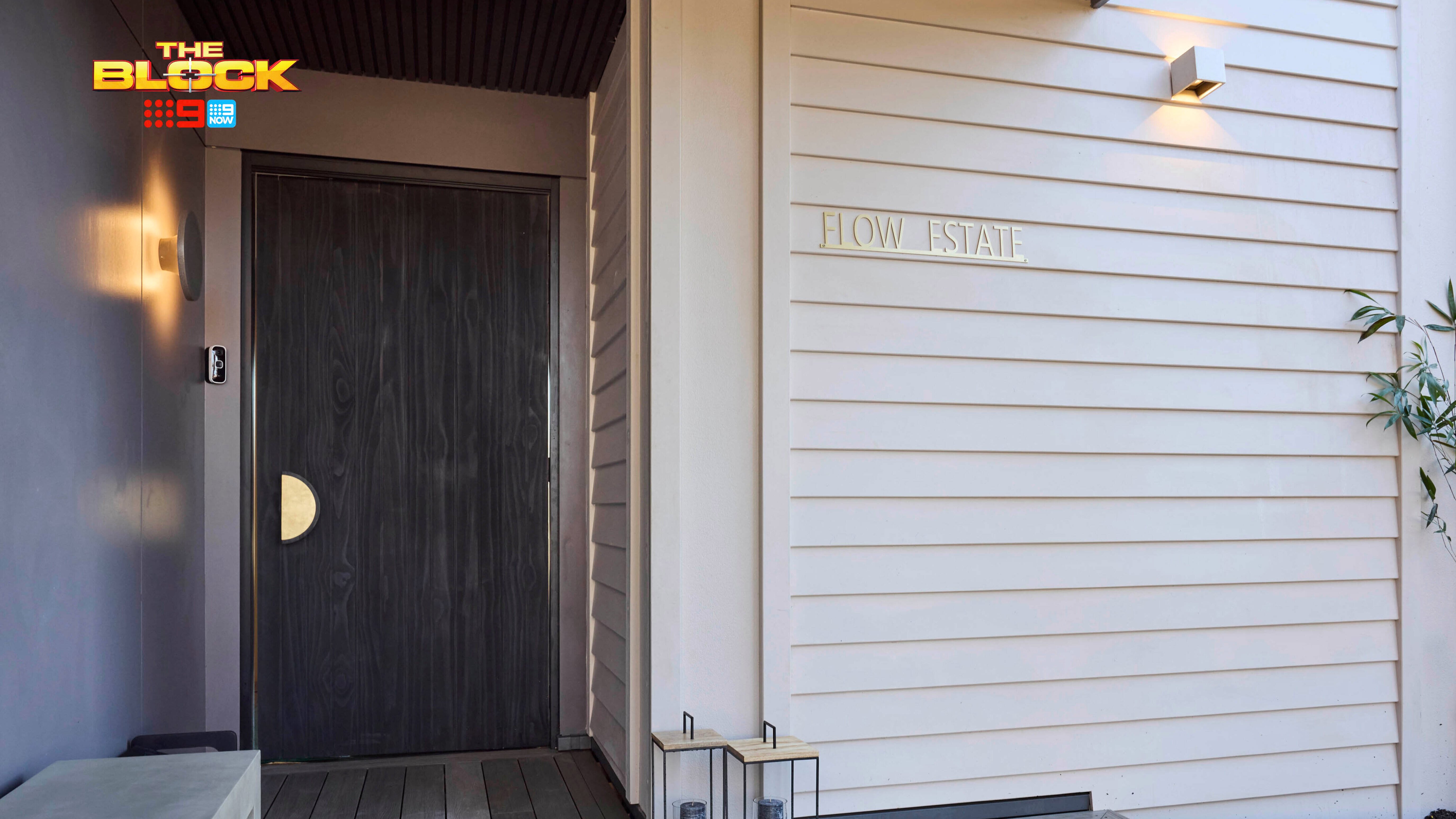 The front entrance of a house with timber decking at the front and lights attached to the house.