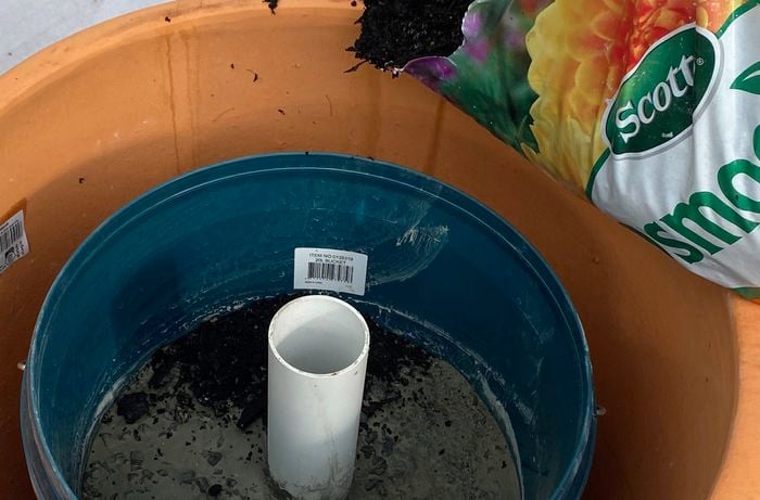 A 20L Bunnings bucket with a white pipe in the centre is filled with setting concrete.