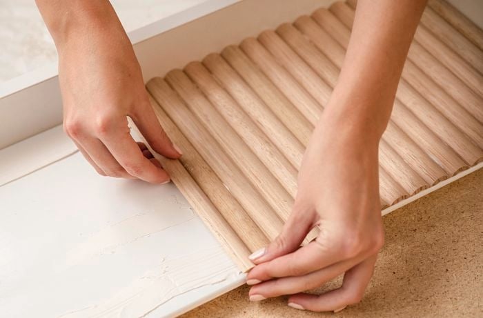 Dowel being laid onto the surface of a vanity with glue