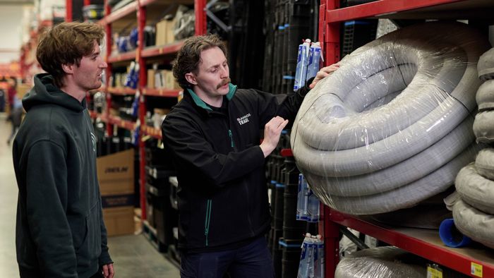 A Bunnings Team Member with their hand on tubing and a customer in a Bunnings store.