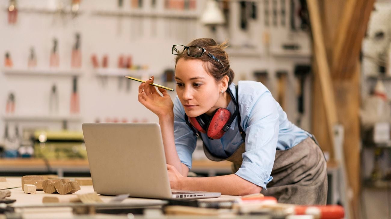 Woman looking at laptop for tax time information in home toolshed.