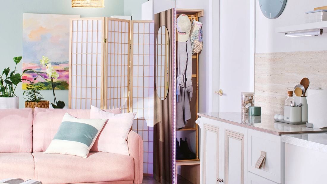 Close up of the corner of an entryway with a compact cloakroom/mudroom at the entrance, a free-standing divider, and a pale pink lounge