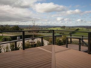 A vineyard view from a wooden deck with a railing.