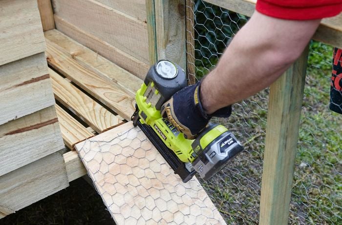 The ramp up to a raised level of a chicken coop being nailed down by a Bunnings team member with a nail gun