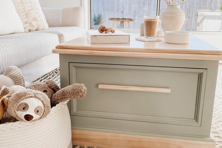 Lime washed coffee table in lounge room, with cream/grey rug, cream cushions and kids dolls