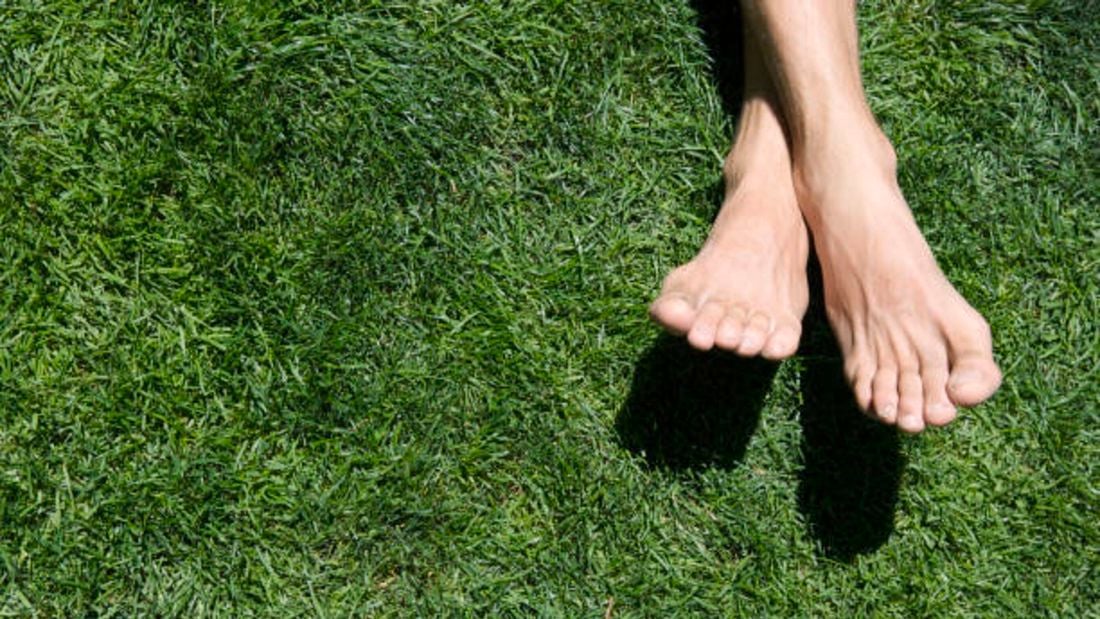 lush green lawn with some's feet relaxing on it.