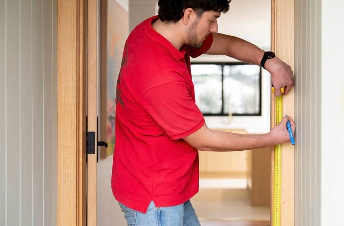 A Bunnings Team Member is marking the mounting location on a door frame that provides a clear view of visitors.
