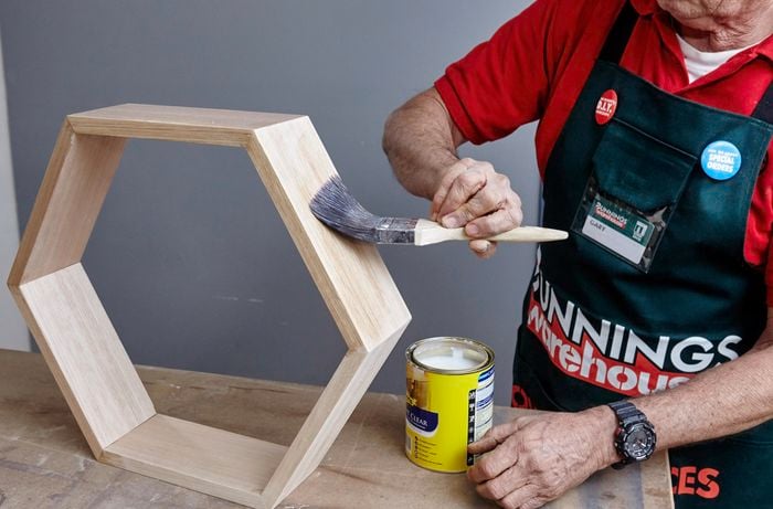Glue being brushed onto the side of a hexagonal shelf ready for gluing to another hexagon