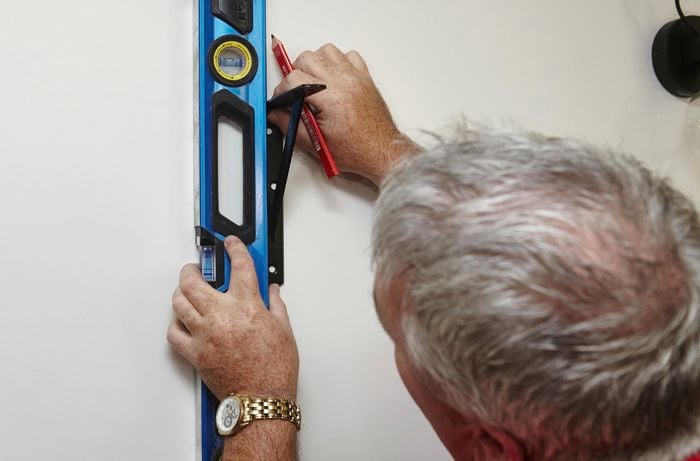 A person positioning a bracket on a wall using a spirit level