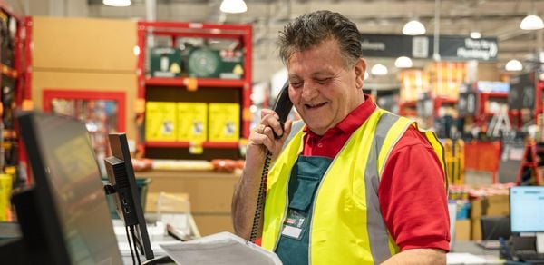 Team member wearing a hi-vis vest on the phone.