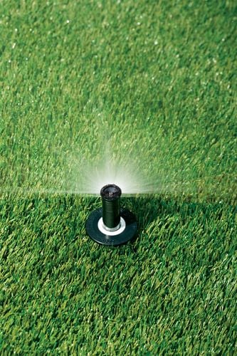 Water spraying out of a pop-up sprinkler in a lawn