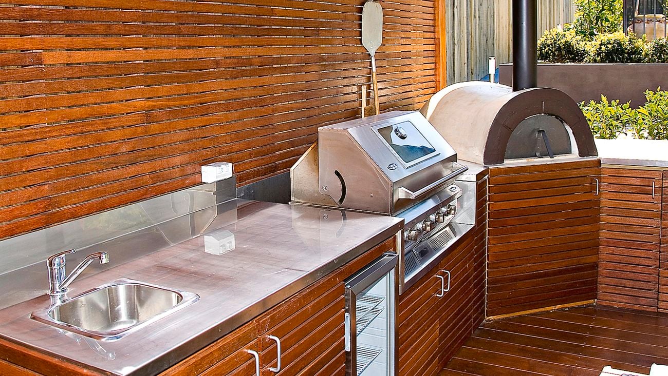 Timber panelled outdoor kitchen with a barbecue and pizza oven