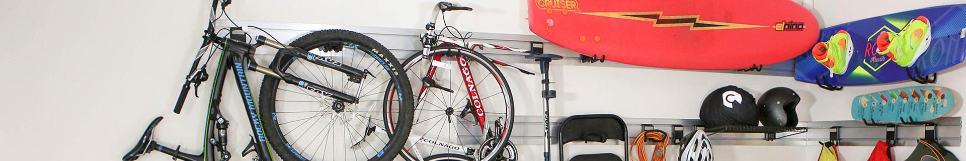 Storage rail with bike, chairs, electrical cords, surf boards and other items hanging.