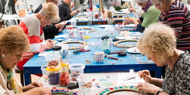 People making tile art together on a table.