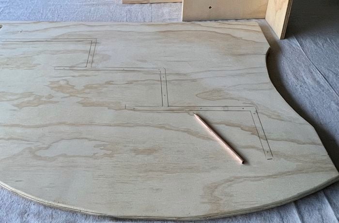 Curved wooden panel on a flat white drop sheet with pencil sitting on top