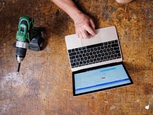An image depicting a tradesperson using Xero accounting software on a laptop placed on a workbench, with a drill also in view. 