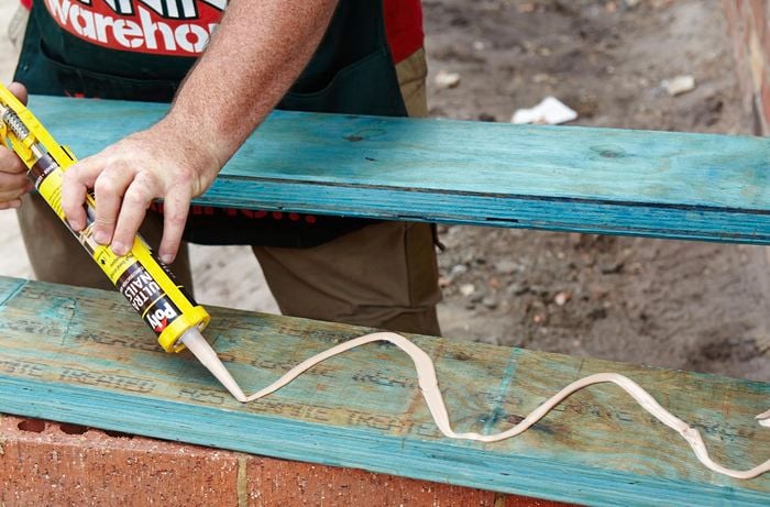 A person applying adhesive to a timber bearer