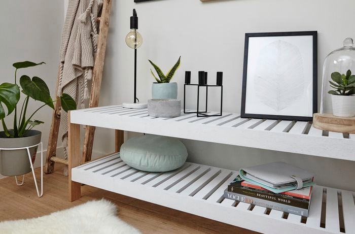 Timber slat shelving unit with books, lamp and indoor pot plants
