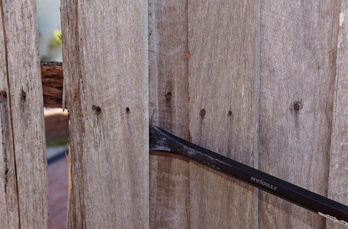 An old fence paling being removed from a fence using a pry bar
