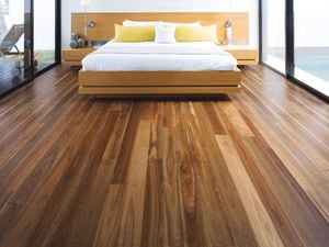 Modern bedroom featuring a timber bed frame and large windows, with polished timber flooring extending across the room.