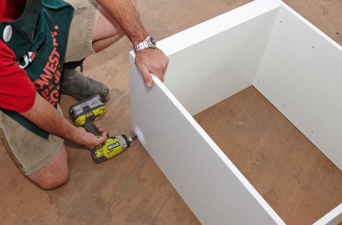 Person drilling to panels together for wardrobe insert unit.