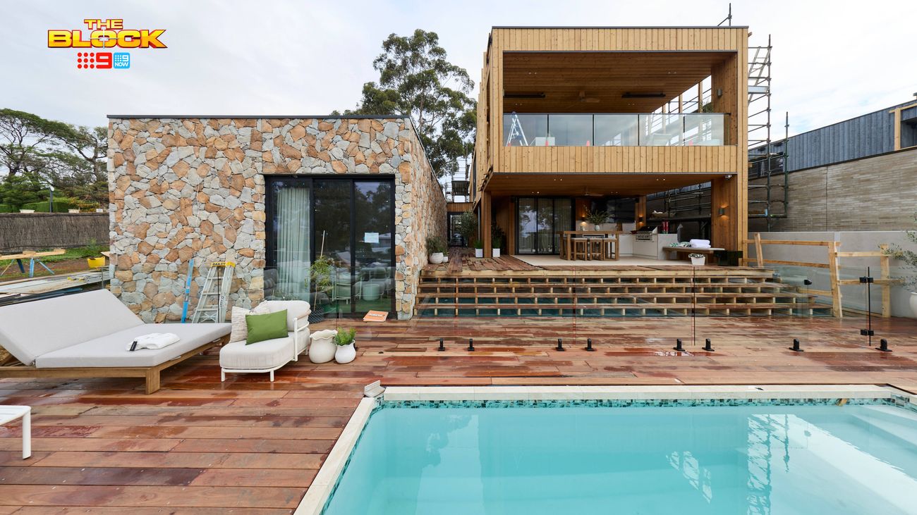Modern two-storey home with timber and stone cladding overlooking a swimming pool and timber deck.