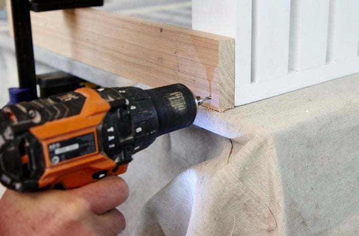 Person attaching table legs to table using drill