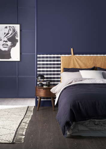 Detail of bedroom painted dark blue with dark blue bedding and timber floor