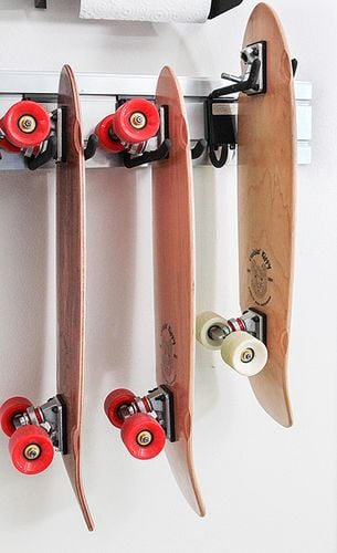 Three skateboards hanging from hooks in a wall mounted rail