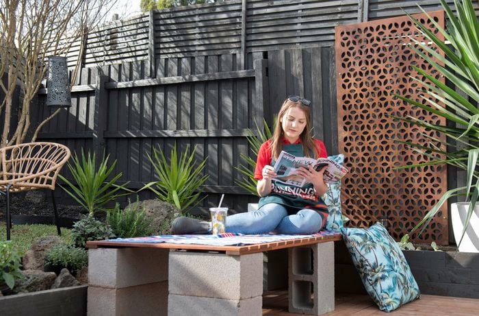 Person sitting on DIY concrete benchtop and reading a magazine.