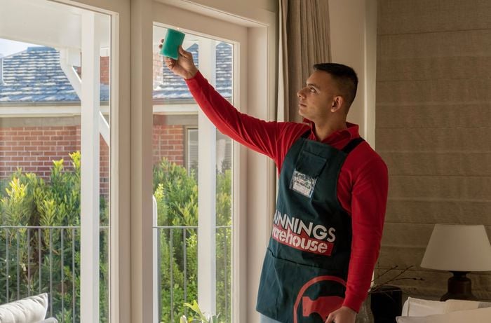 A person holding up a candle in front of a window seal.