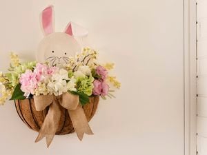 Hanging coir-lined wall basket with pastel flowers and a bow, a paper plate bunny face with pink ears peeking over the top