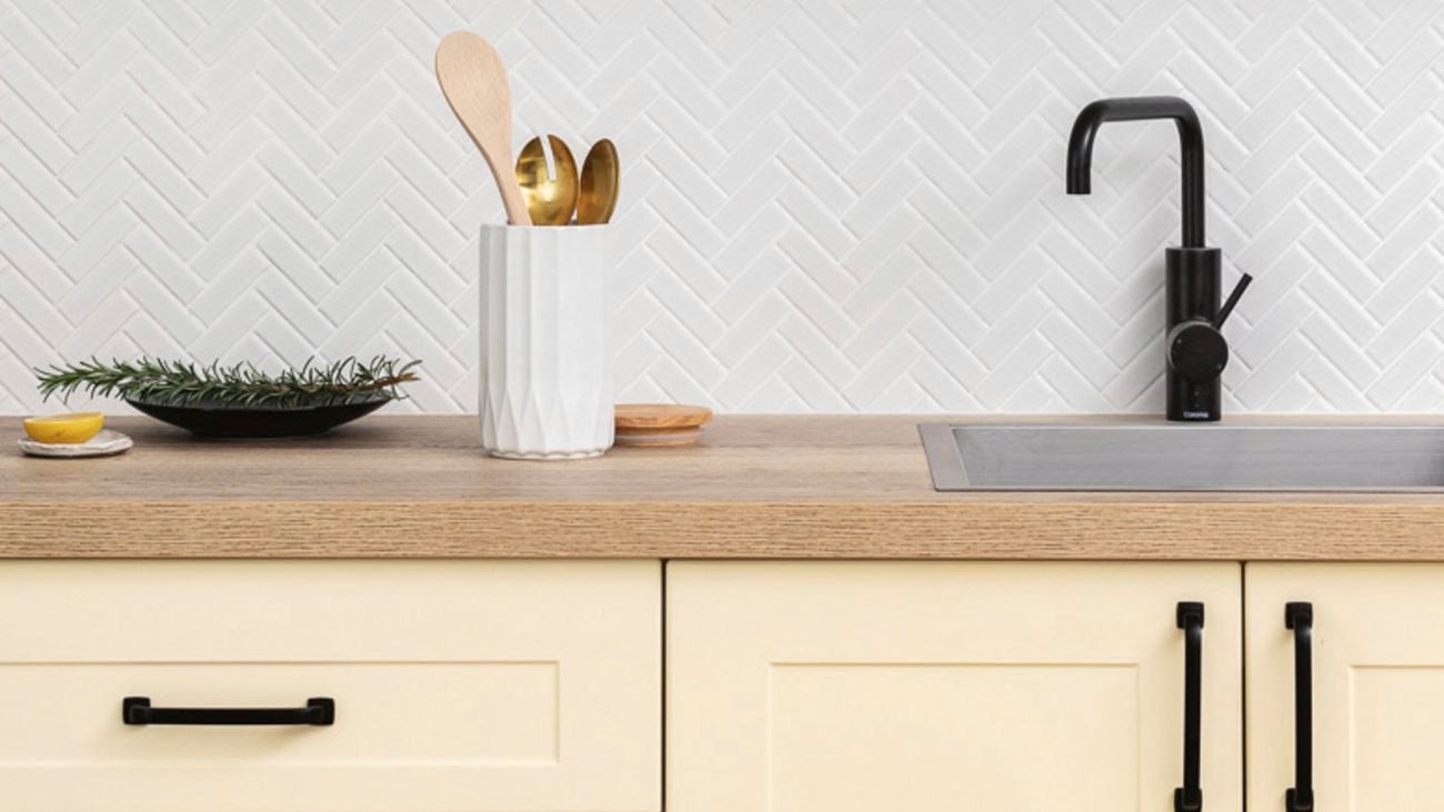 Yellow-cream coloured kitchen cabinets with matte black hardware