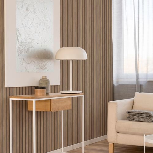 Living space with timber look wallpaper, side table with lamp and large wall print.