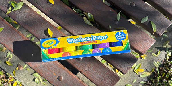 Pack of Crayola washable paint in five classic colours displayed on a wooden outdoor table.