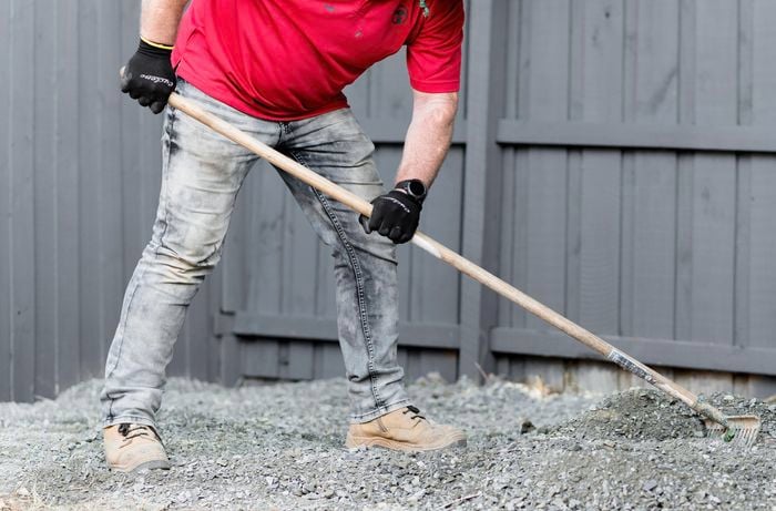 Person spreading out gravel with a rake.