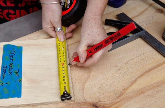 A plank of wood being marked with a ruler and tape measure