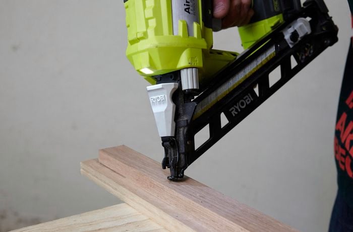 Person using nail gun to nail timber pieces together