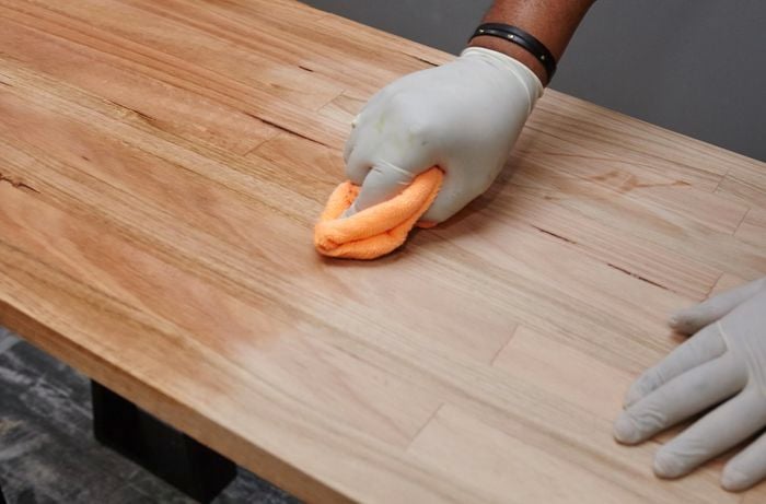 A person applying oil to a table top