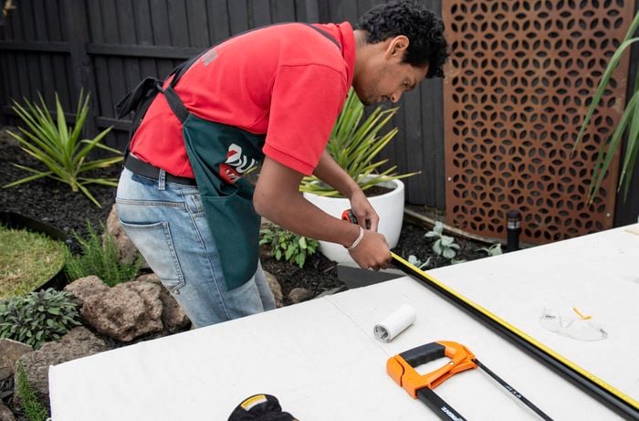 A Bunnings team member measuring a length of metal pipe