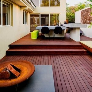 Decking with an outdoor table, outdoor bench and chairs on it at the back of a house.