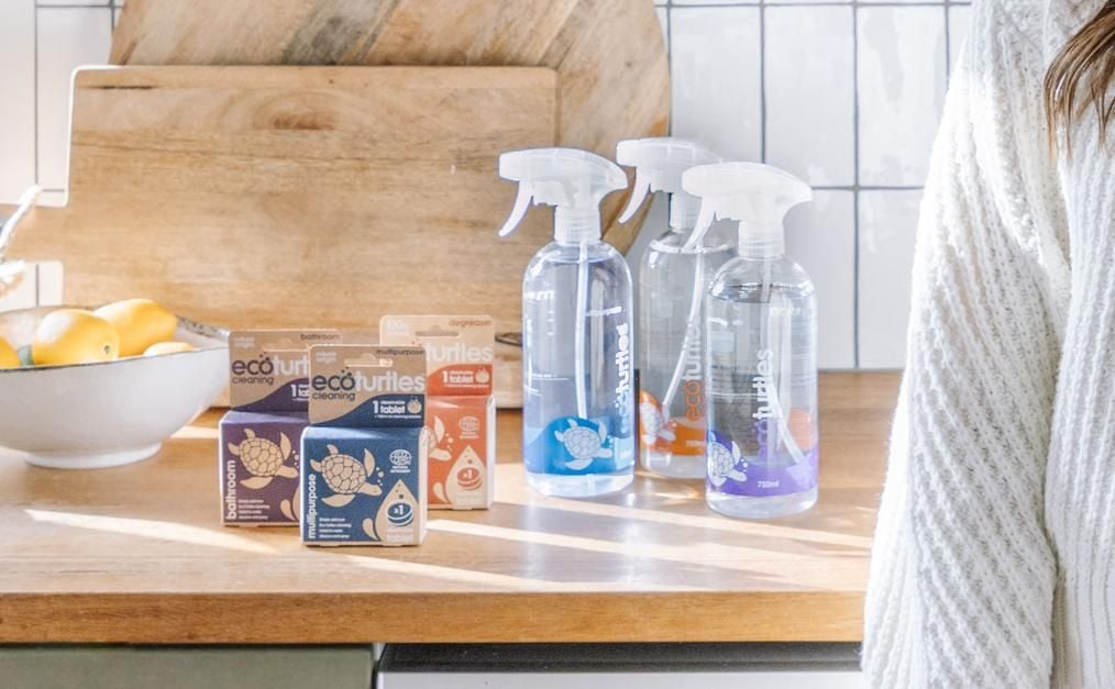 Woman standing in kitchen next to the Eco Turtle cleaning products on the bench