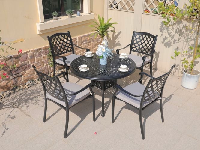 A cast aluminium outdoor dining setting with four chairs and a table