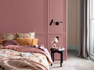 luxe bedroom with soft pink walls and timber side table