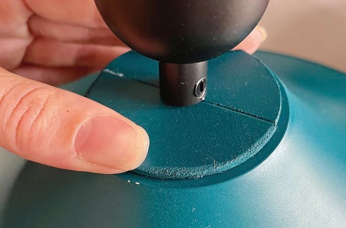 A person secures an MDF disc to the top of an upcycled lampshade.