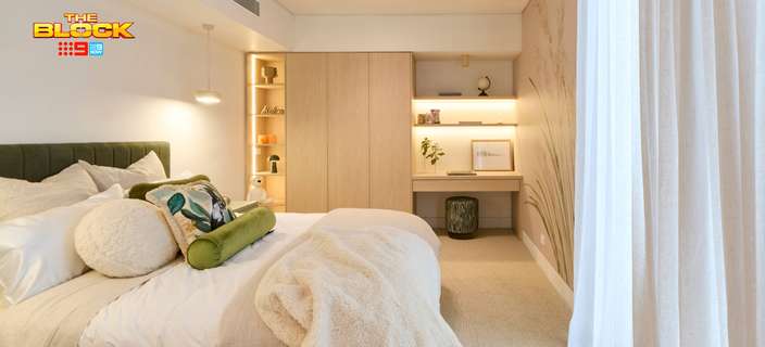 Contemporary bedroom featuring neutral bedding, a timber bed frame, built-in wardrobes and a study nook with open shelving.