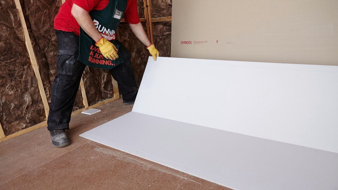 A Bunnings team member placing a half-height sheet of plasterboard against a wall