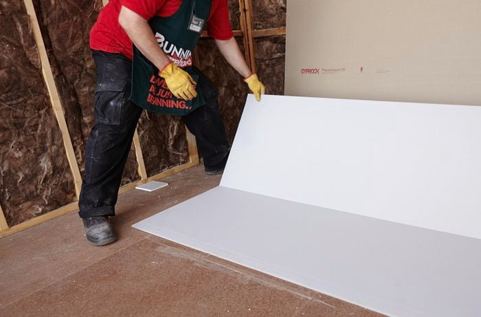 A Bunnings team member placing a half-height sheet of plasterboard against a wall