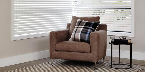 Couch with venetian blinds behind.