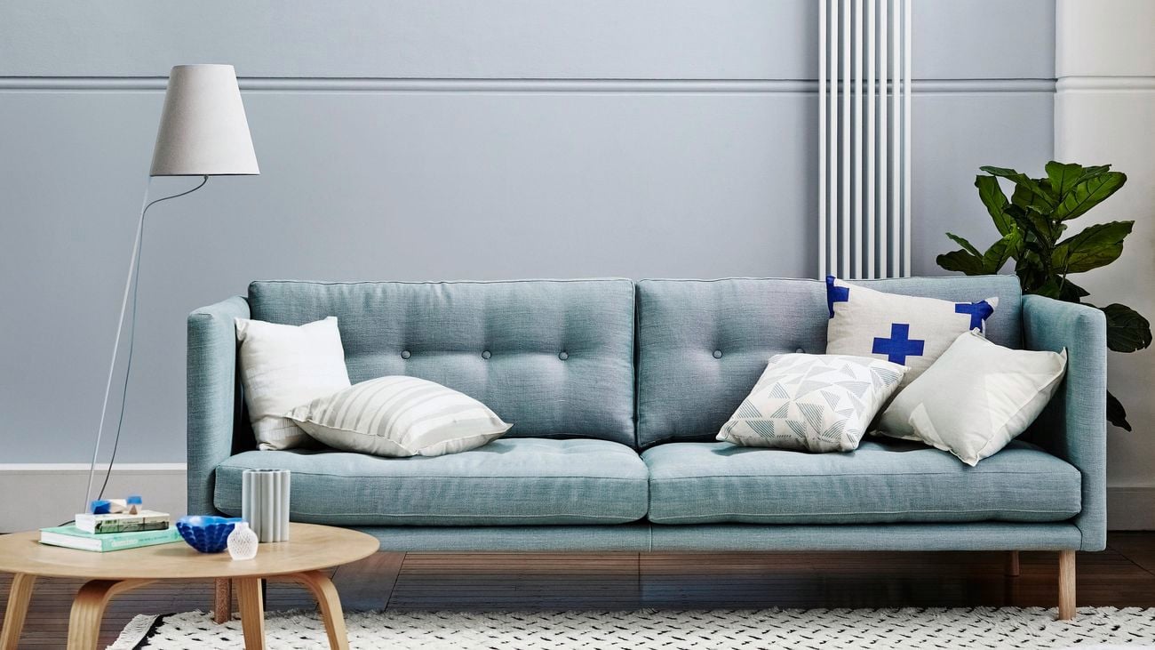 A blue couch in a living room with grey walls.